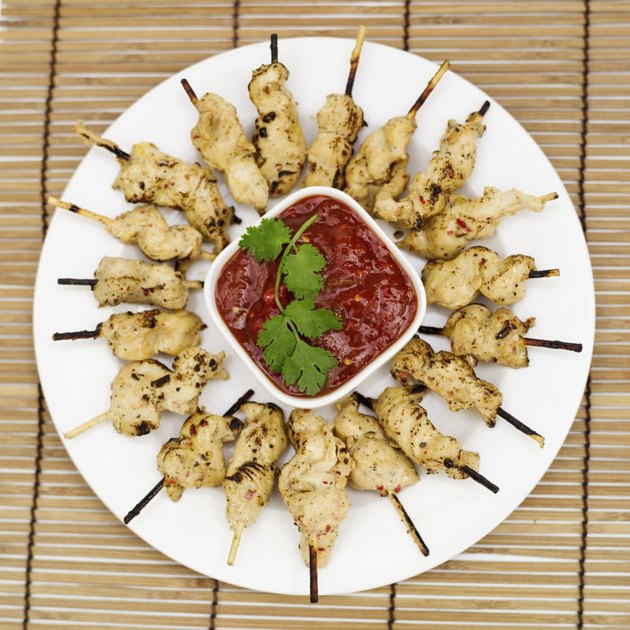 Vue élevée d'une assiette de brochettes de poulet sur des brochettes avec sauce au centre de l'assiette